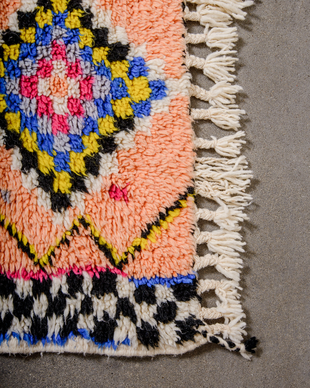 Corner of Berber runner rug with fluffy wool pile, tightly woven end and natural wool tassels.